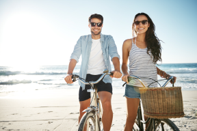 Couple riding bikes on the beach smiling wearing prescription sunglasses uv protection