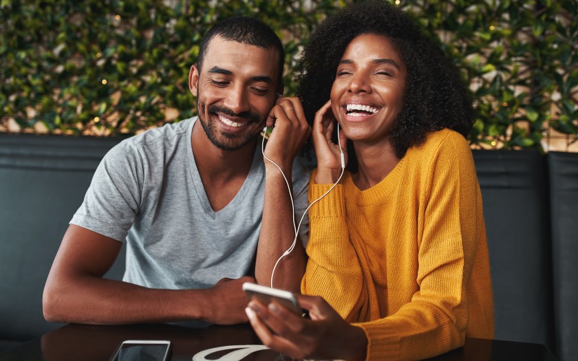 Young couple sharing headphones laughing