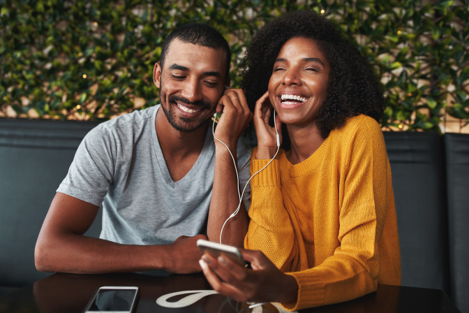 Young couple sharing headphones laughing
