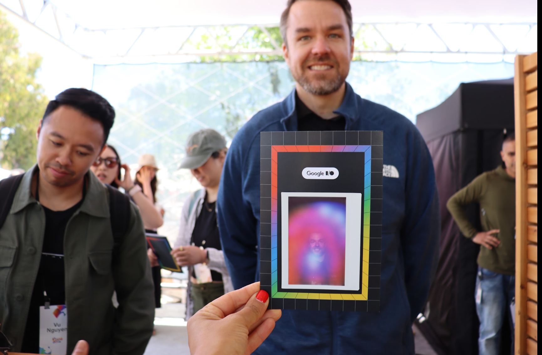 A%20guest%20holds%20up%20his%20printed%20aura%20photo%20at%20an%20outdoor%20event%20while%20others%20wait%20their%20turn.%20Photo%3A%20The%20Aura%20Journey.