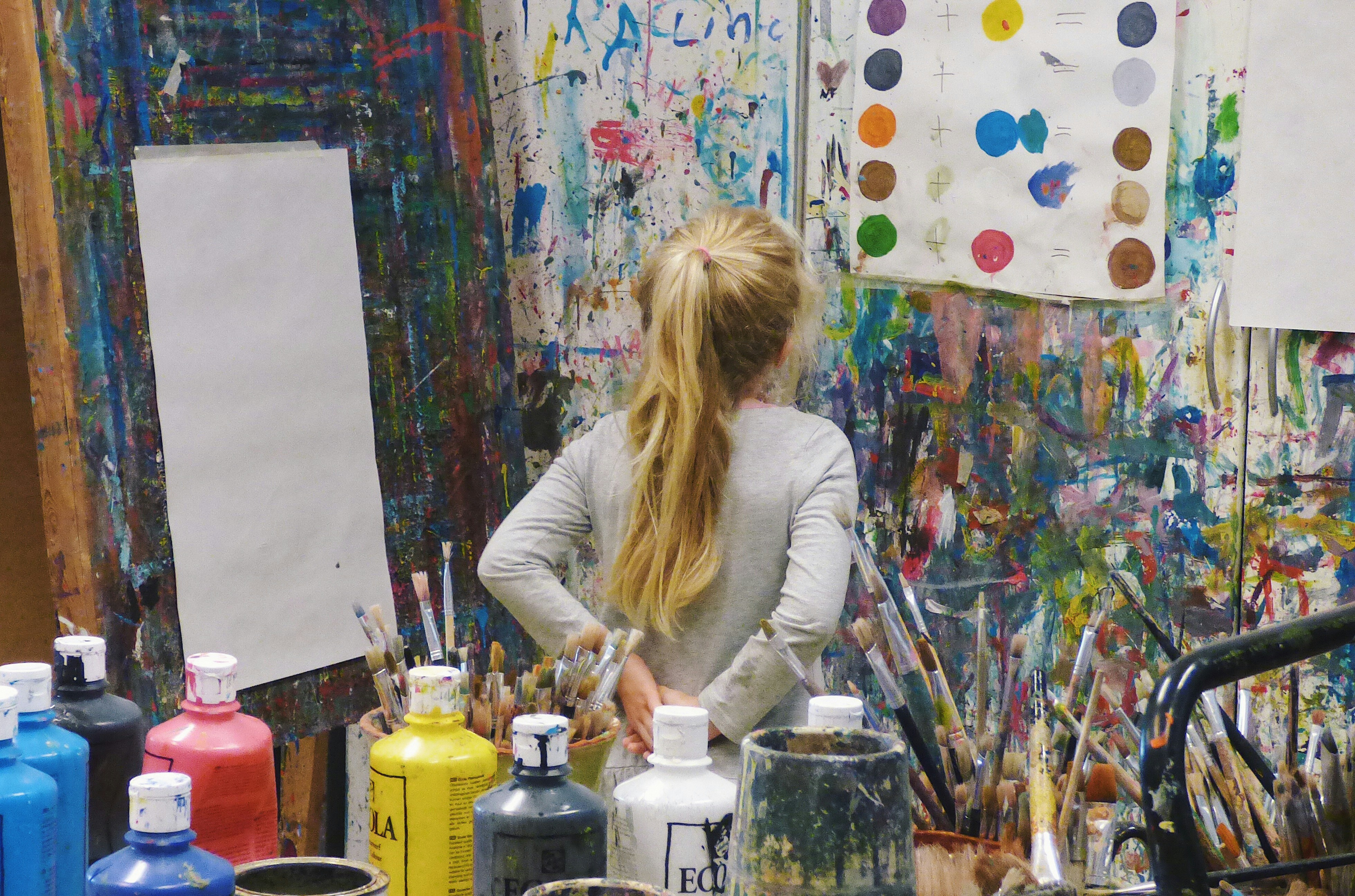 Youth painting at easel in colourful studio during Dryden Campus art workshop, exploring painting techniques and colour.