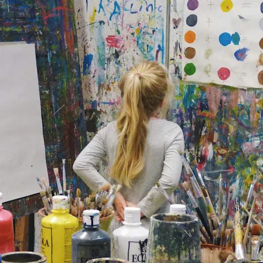 Youth painting at easel in colourful studio during Dryden Campus art workshop, exploring painting techniques and colour.