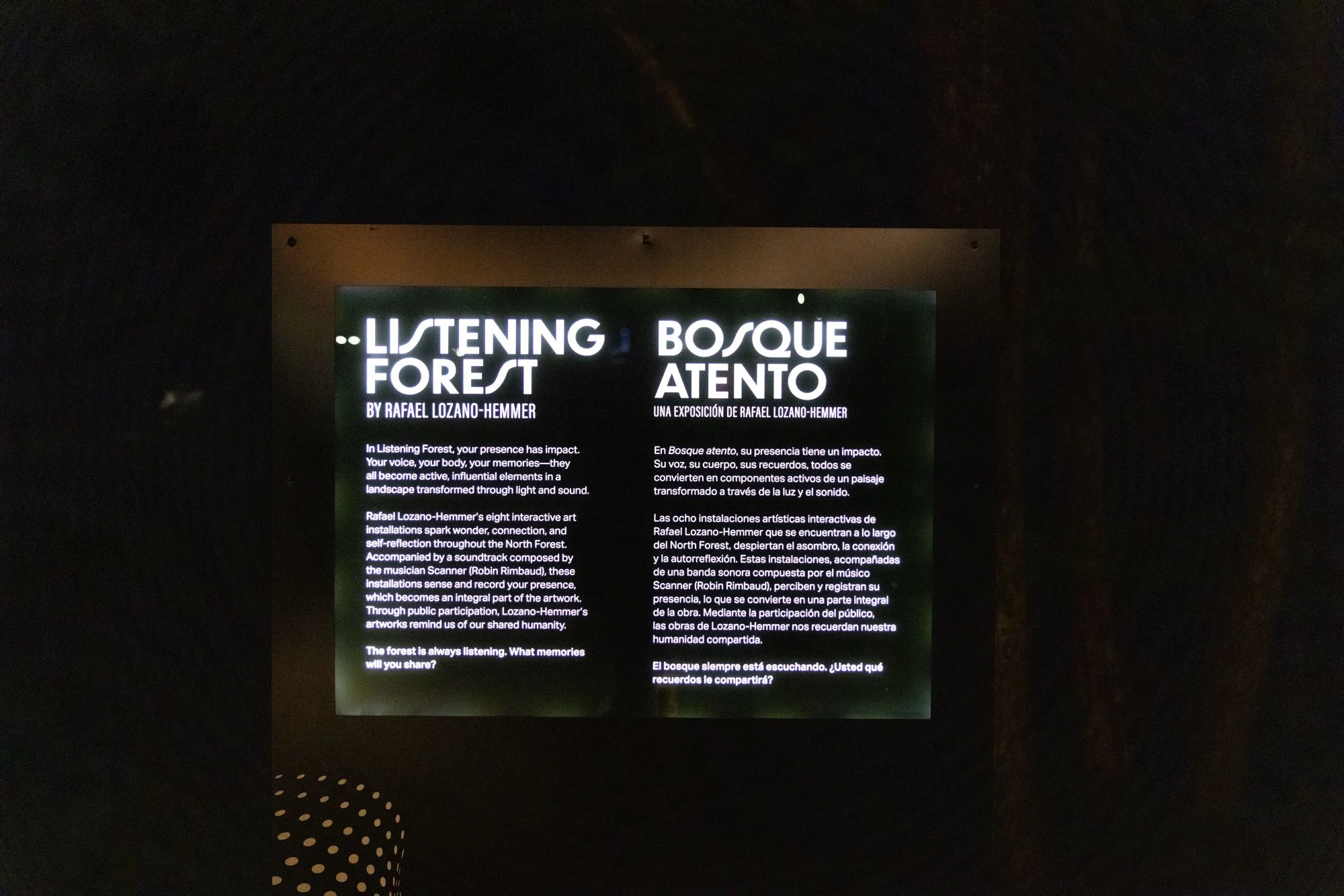 A lit kiosk label with the headline "Listening Forest, Bosque Atento."