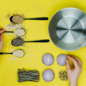flat lay photography of saute skillet beside spoon of spices and vegetables