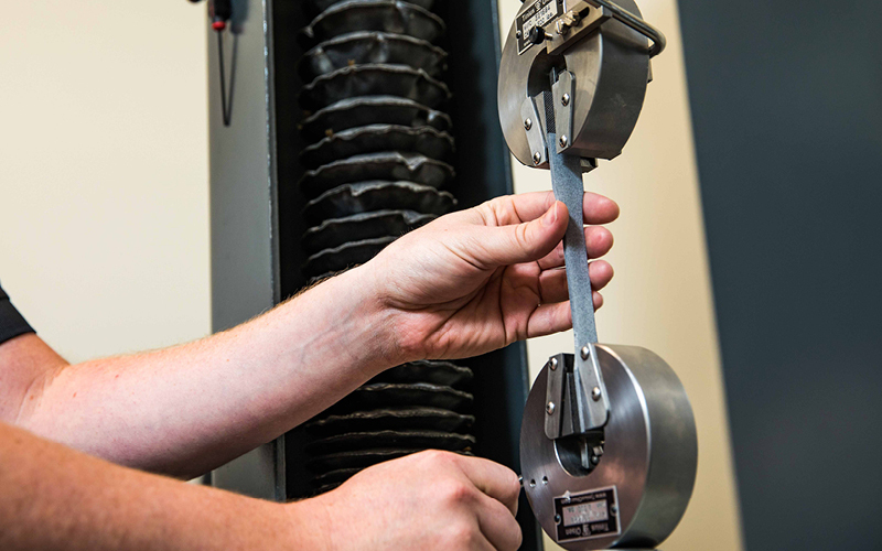 A close-up of a tensile strength testing machine evaluating the durability and flexibility of a material sample.