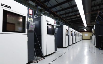 A row of industrial FDM printers in a controlled build room.