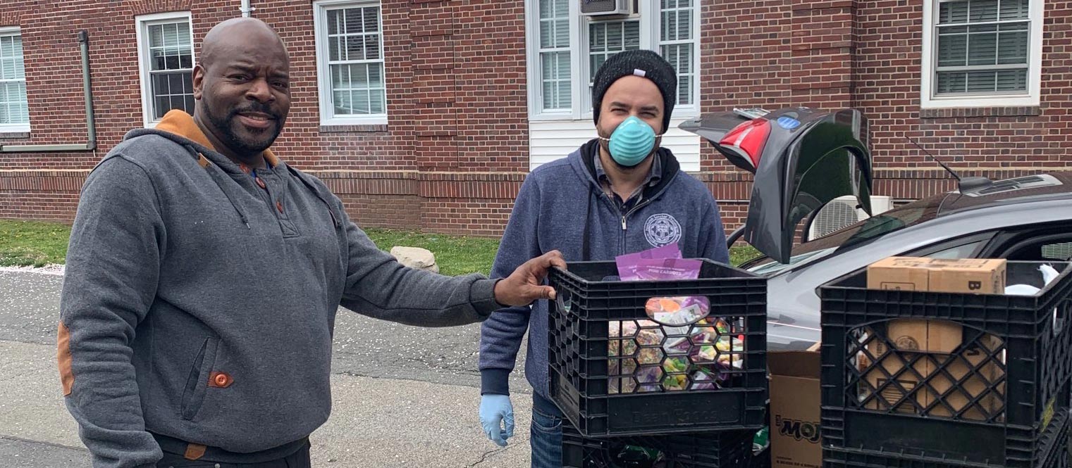 Two volunteers loading up a car with supplies of food