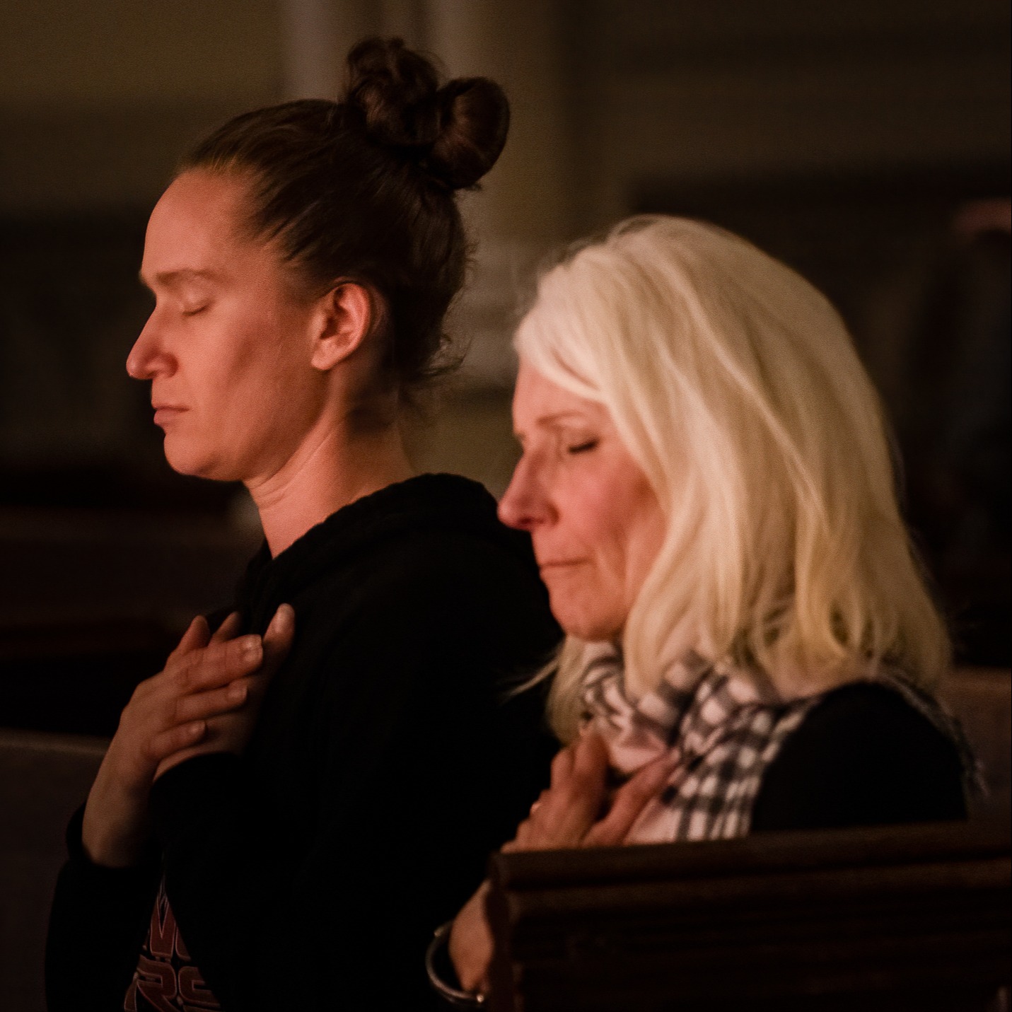 Two women silently praying with eyes closed