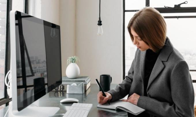 Freelance woman writing in front of a computer.