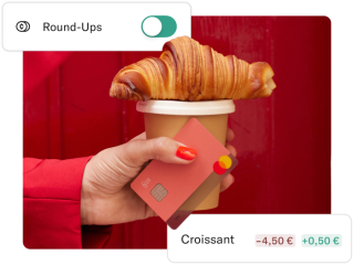 A hand grabbing a cup of coffee, a croissant, and an N26 Rhubarb card.