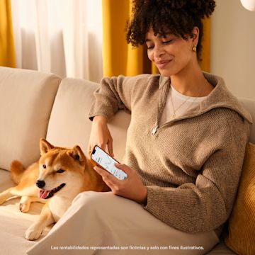 Mujer sentada en un sofá mirando la aplicación N26 con su perro.
