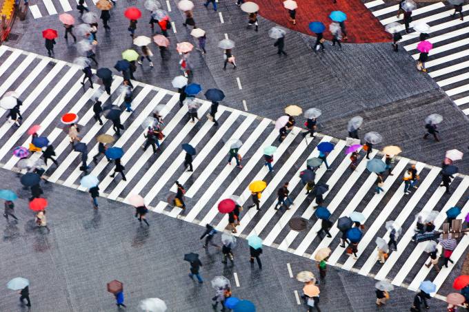 Un cruce de peatones con personas sosteniendo sombrillas de diferentes colores.