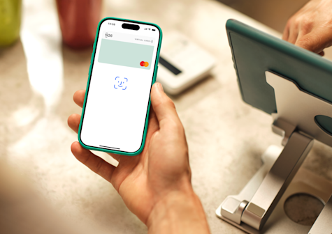 Una persona sostiene un smartphone que muestra la aplicación de banca móvil N26 con una tarjeta virtual y un ícono de Face ID.