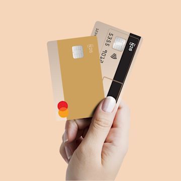 An elevated hand holding two N26 cards against a beige background.