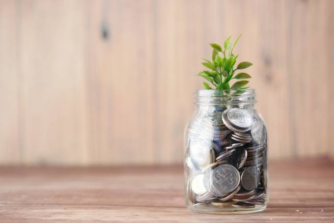 Glas mit Münzgeld welches durch Sparen und Zinseszinsen langsam wächst.