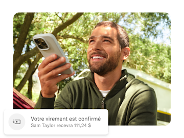 Un homme tient son téléphone portable, sous lui se trouve une notification push concernant son transfert d'argent international.