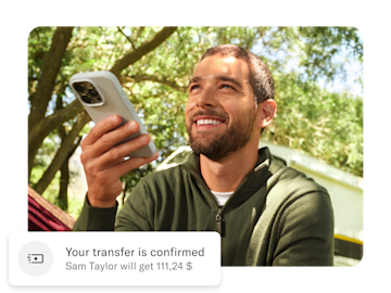 Man holding his mobile phone, below him is a push notification about his international money transfer.
