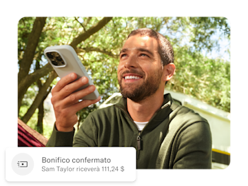 Uomo che tiene in mano il suo telefono cellulare, sotto di lui c'è una notifica push sul suo trasferimento di denaro internazionale.