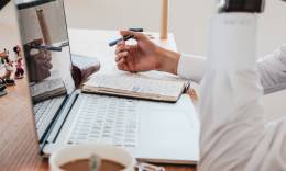 Un uomo libero professionista che lavora ad un computer portatile e che beve caffè.