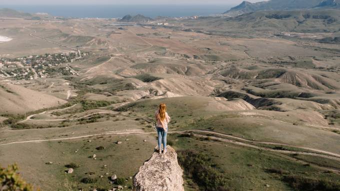 Donna in piedi sulla cima di una piccola montagna.