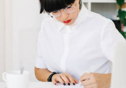 Mujer trabajando en su escritorio con una taza de café.