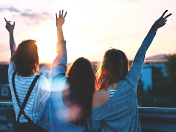 Tres estudiantes que miran la puesta de sol.