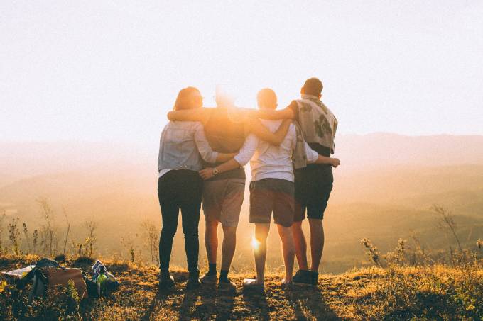 Group of people hugging by the sunset. 