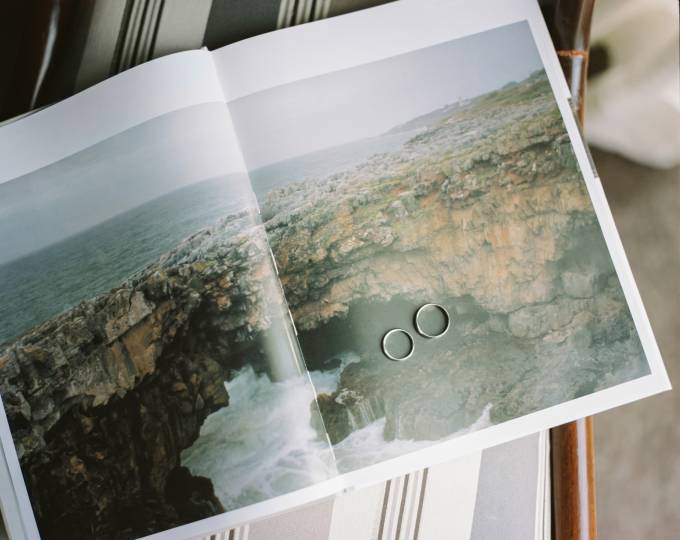 libro abierto con una buena foto de un acantilado y con dos anillos de boda sobre la imagen.