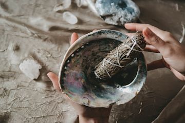 Hands holding a bowl with dried herbs.