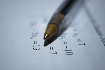 A pen on a piece of paper with numbers.
