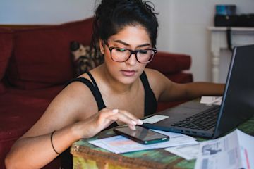 Frau mit einem Laptop und einem Smartphone.