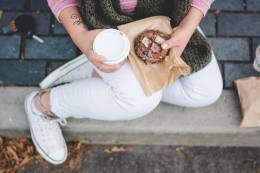 Person sitting holding coffee and a pastry. 