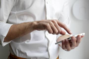 Primo piano delle mani di un uomo che controlla il suo smartphone.