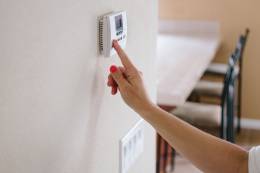 Woman adjusting a thermostat.