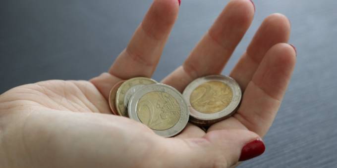 Eine Frau hält mehrere Euromünzen in der Hand.