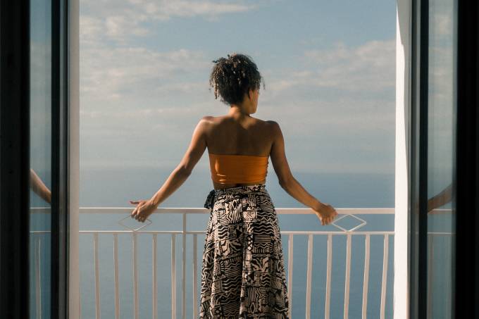 Woman looks out from a balcony.