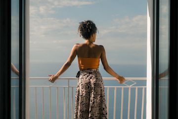 Woman looks out from a balcony.