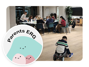 In an office space, several adults are seated at a table, while a young boy plays with a toy car on the floor. A circular graphic with the words "Parents ERG" and an illustration of three smiling figures is in the foreground.