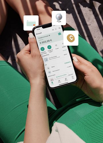 Personne en costume vert assise et tenant un téléphone portable avec l'application n26.