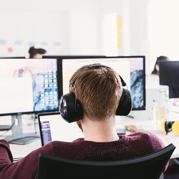 Man working in front of a computer with headphones.