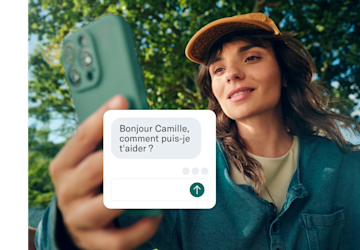 Une femme tient son téléphone vers l'appareil photo, avec une boîte de discussion de service client superposée à l'écran.