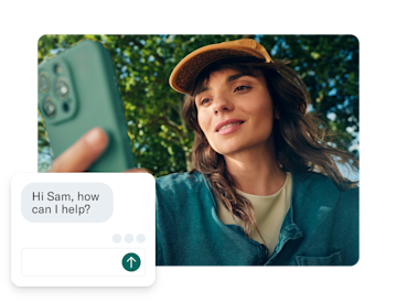 A woman holds her phone toward the camera, with a customer service chat box overlaid on the screen.