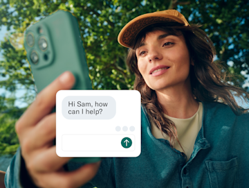 A woman holds her phone toward the camera, with a customer service chat box overlaid on the screen.