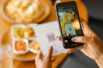 A hand with a phone scanning a QR code.