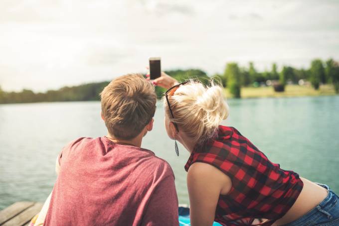 A couple having a summer date and sitting in the deck of a lake. 