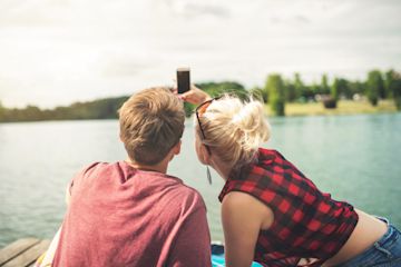 A couple having a summer date and sitting in the deck of a lake.
