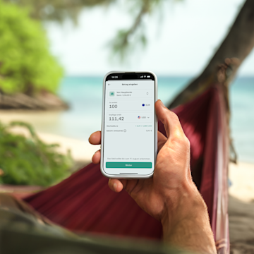 Hand hält ein Mobiltelefon, auf dem eine internationale Banküberweisung in der N26-App angezeigt wird.