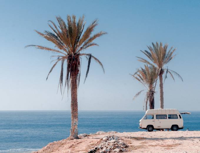 Furgoneta en la playa con palmeras.