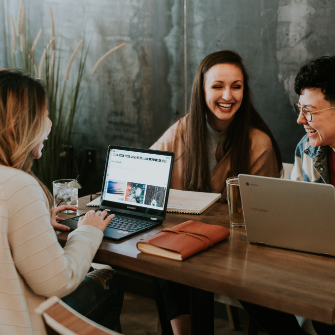 A group of students chat and work on the computer.