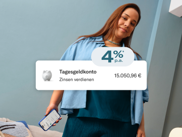 Eine blau gekleidete Frau sitzt da und hält ihr Handy in der Hand, während die N26-Anwendung geöffnet ist. Im Vordergrund Bild der 4 % p.a. Zinssatz, Guthaben auf dem Hauptkonto und auf dem Sparkonto.